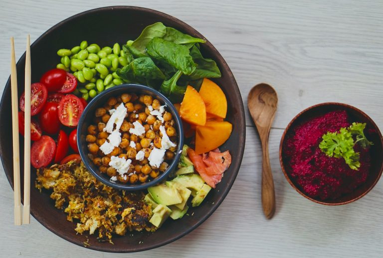 charlotte-karlsen-DAih2b5MFcA-unsplash | Many Words One Voice Make Reaping the Benefits of Healthy Eating Sustainable by keeping the traditions that work for you, Pictured: a wooden bowl filled with a bright salad, chopsticks lay on the left side of the bowl.